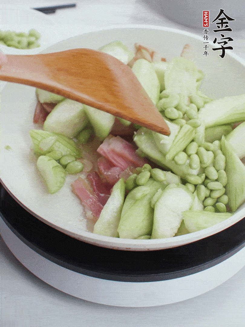 依次下絲瓜、青豆翻炒，炒至絲瓜打蔫縮小。