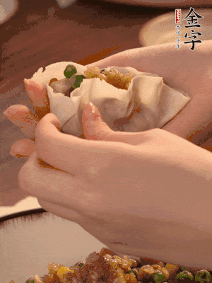 取一大勺餡料放進(jìn)餃子皮里，用大拇指按住頂部餡料，再用虎口掐出形狀。