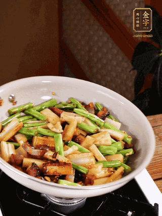 油熱下蒜末、干辣椒、醬肉煸炒出香味，依次下藕條、豆角翻炒均勻